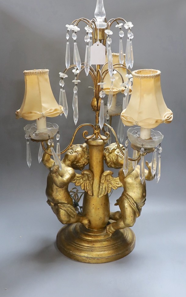 An Italian three branch gilt composition cherubic lamp with cut glass lustre drops - 64cm high
